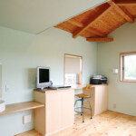 天井の木組みと無垢材の床が温もりを感じさせる個室。デスクや洗面台を造作でまとめ、機能性とデザインを両立しました。 館山の家 2階個室 無垢材の床と木組み天井のあるワークスペース